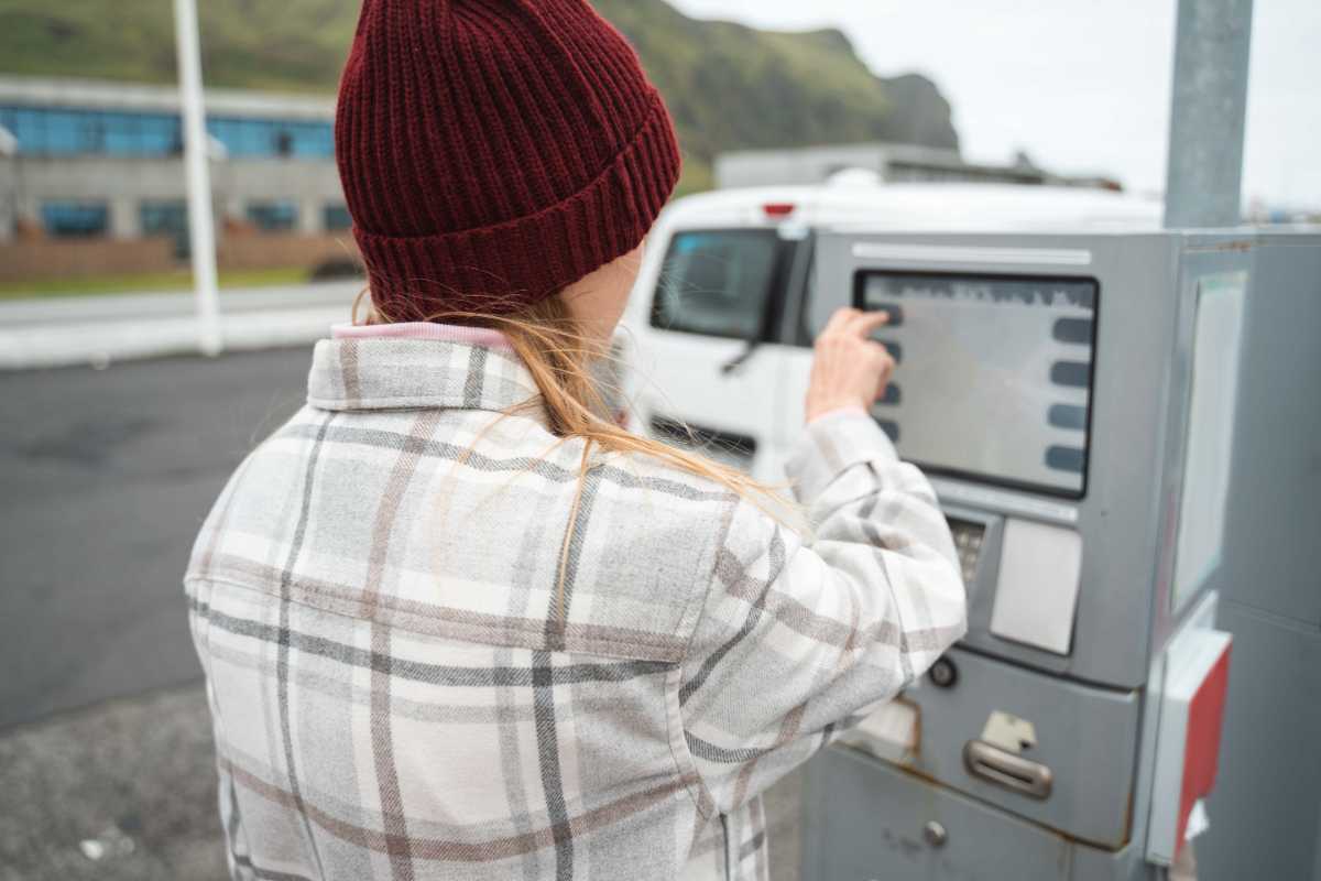 Les facteurs économiques maintiennent les prix à un niveau élevé en Islande Une femme portant une casquette et une chemise à carreaux manipule un pistolet de distribution de carburant en Islande.