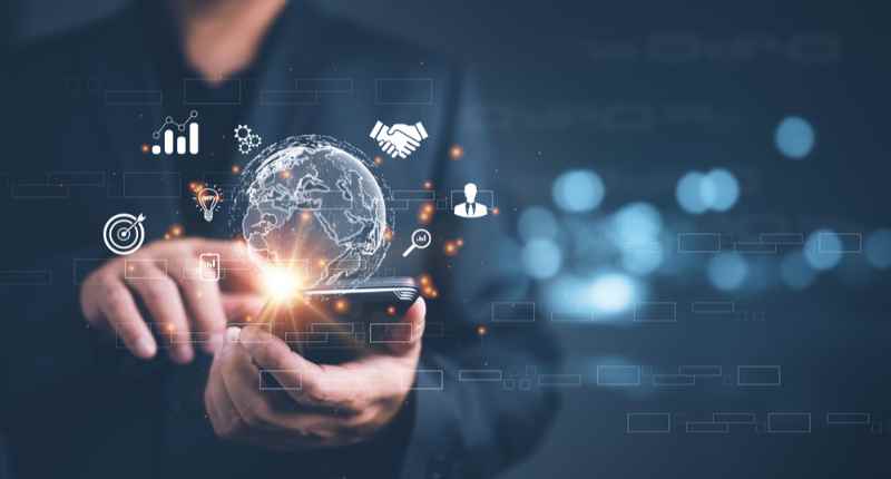 Homme d'affaires utilise un smartphone tandis que des ic&ocirc;nes num&eacute;riques comme un globe et des graphiques commerciaux flottent dans l'air.