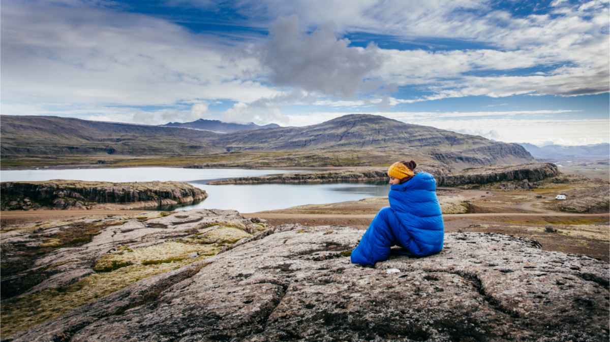 Objets utiles à emporter en Islande en avril Touriste dans un sac de couchage chaud en Islande