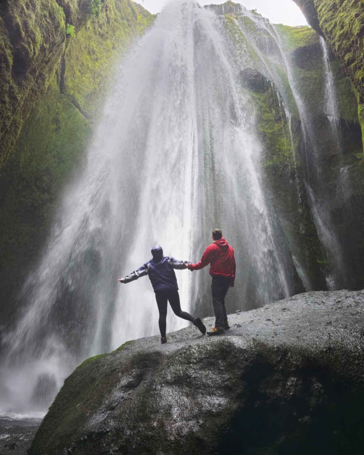 Couple debout sur un rocher face à Gljúfrabúi