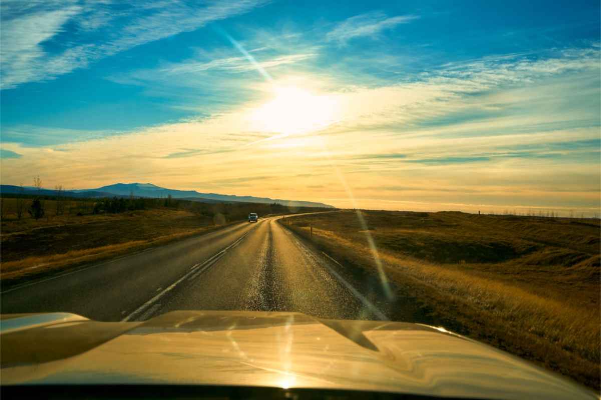 Route islandaise avec le soleil de minuit face au pare-brise
