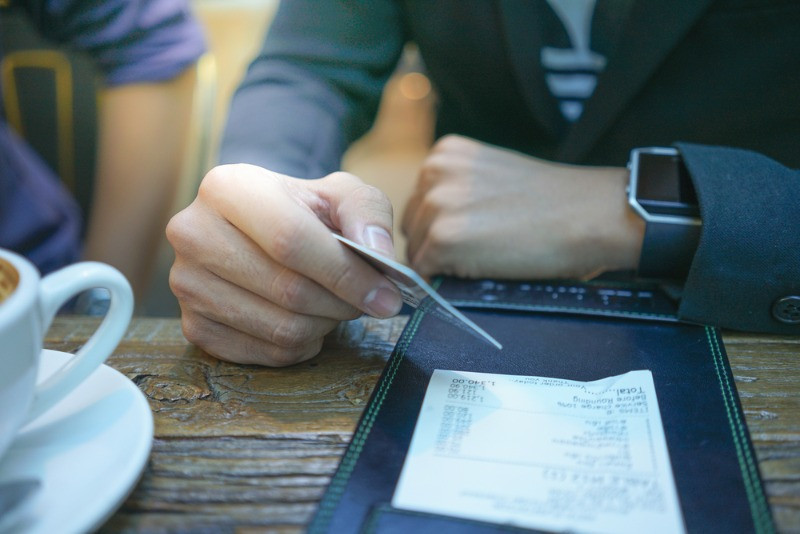 Client payant l’addition d’un restaurant avec une carte de crédit.