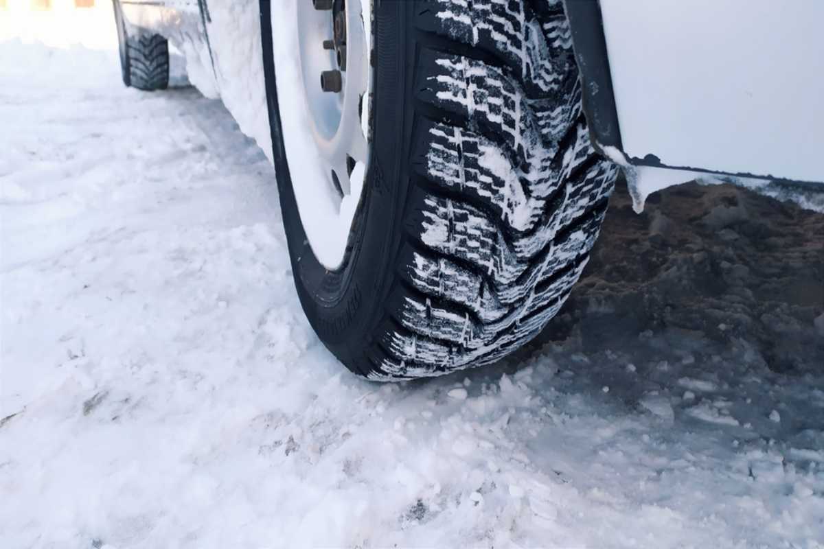 Pneumatici invernali per guidare in inverno in Islanda Primo piano di uno pneumatico invernale su un veicolo parcheggiato su neve e ghiaccio in Islanda