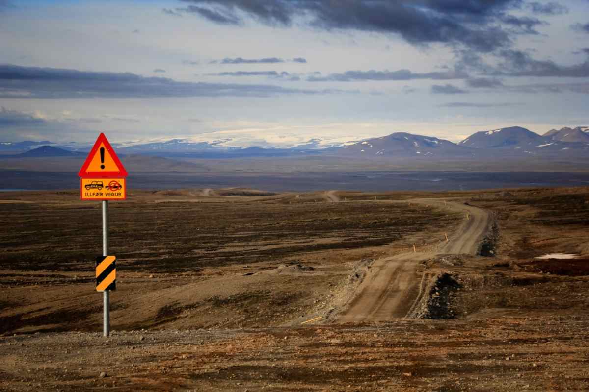 Consigli di sicurezza per guidare sulla F35 Segnale di avvertimento accanto a una strada sterrata sconnessa sulla F35 negli Highlands islandesi