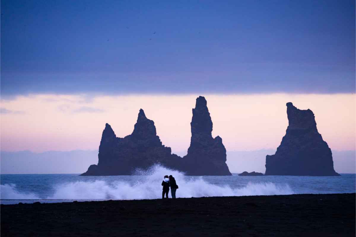 I migliori luoghi per una proposta in Islanda Coppia sulla spiaggia di sabbia nera Reynisfjara in Islanda