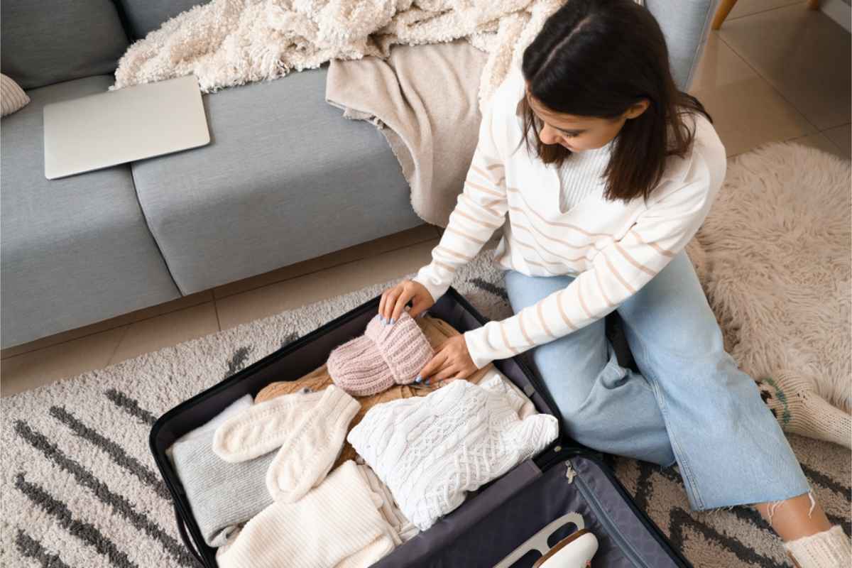 Donna che prepara vestiti invernali per il suo viaggio