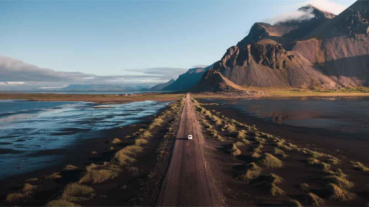 Auto bianca che guida verso il tramonto vicino al monte Vestrahorn in Islanda