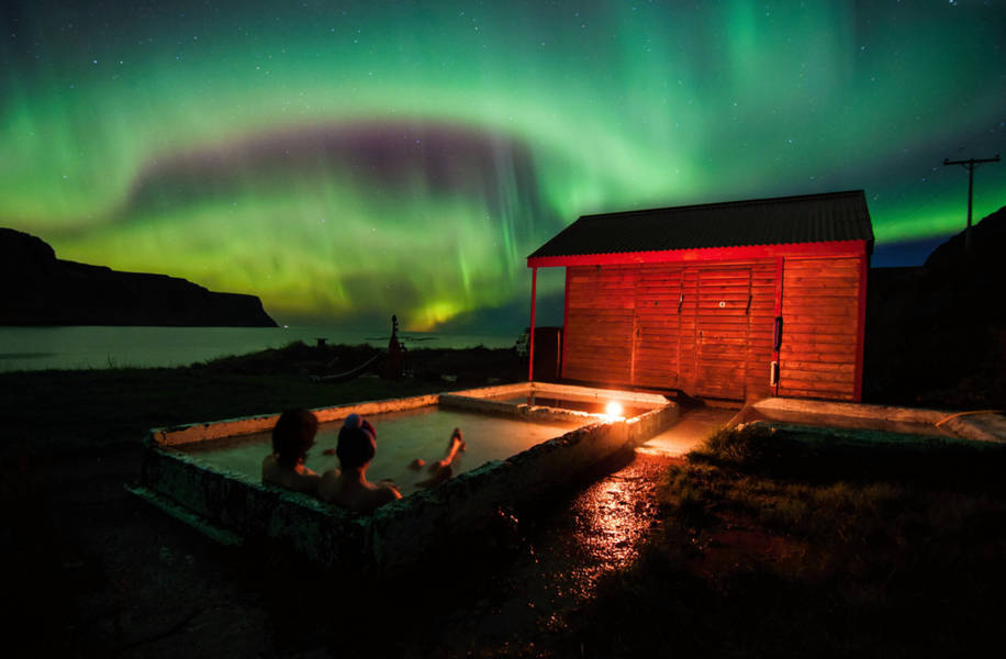 Couple watching the Northern Lights from a geothermal jacuzzi